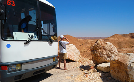 A tourist takes in a canyon view from outside a charter bus rental